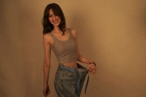 Mujer muestra su pérdida de grasa sosteniendo unos jeans holgados que antes le quedaban ajustados